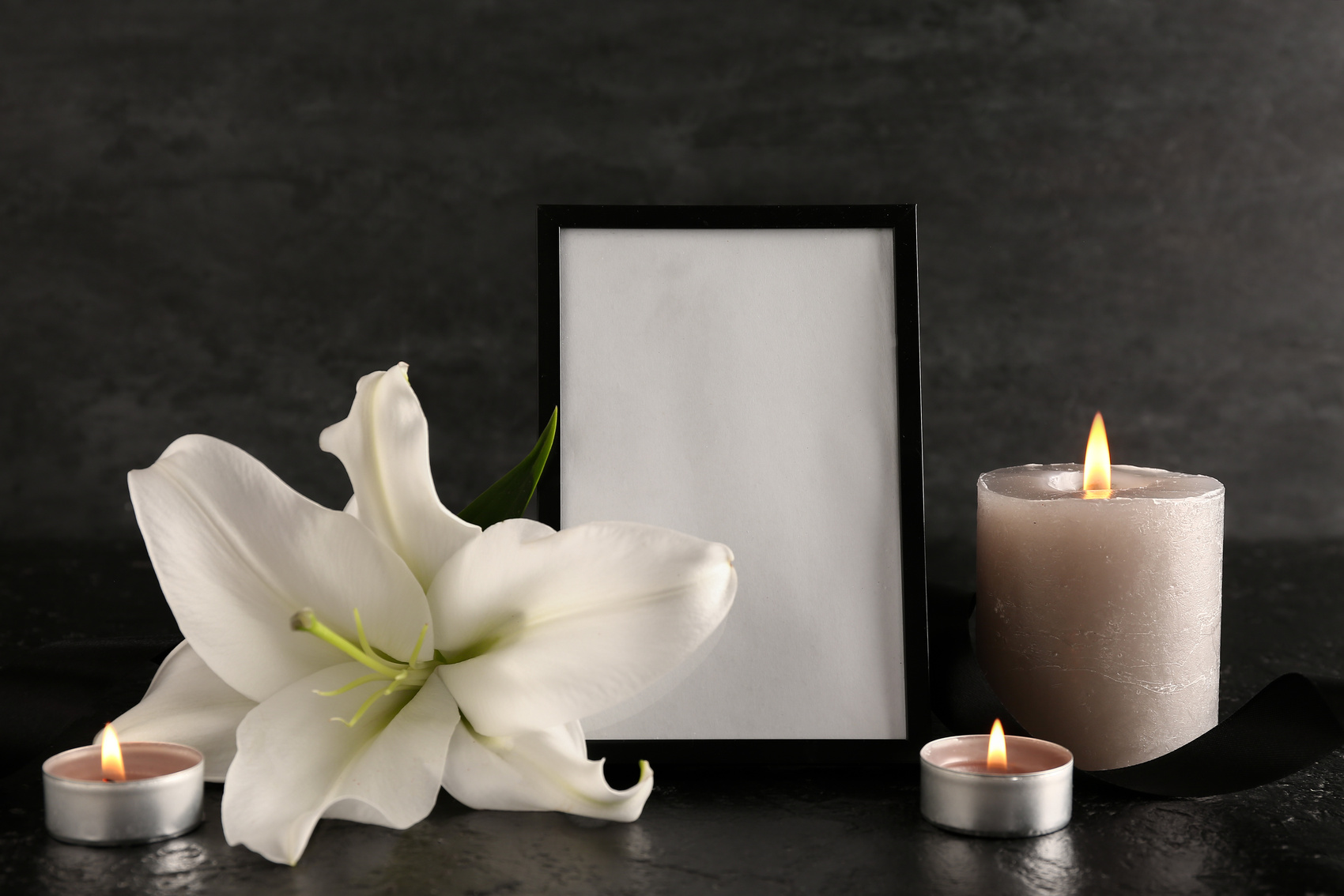 Photo Frame with Burning Candles and Lily Flower on Black Grunge Table